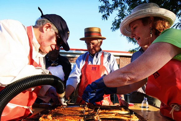 Rotary Club members from Essex, Conn., remove the nails pinning shad to cedar planks for roasting. The organization has been holding a shad festival in the river town for more than 50 years. Credit: Richard Levine