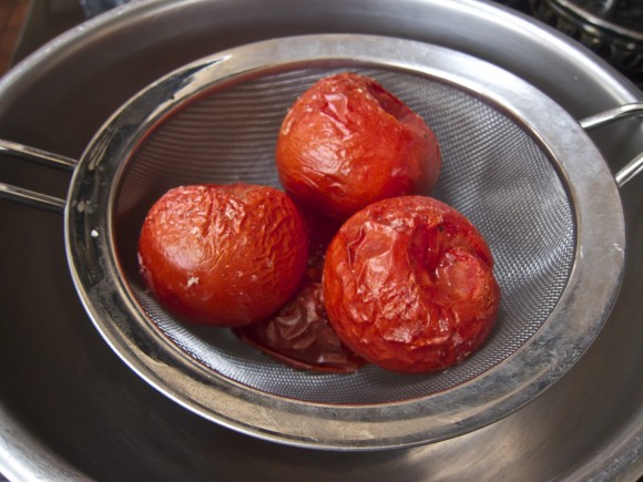 Roasted tomatoes in a wire mesh strainer over a nonreactive bowl. Credit: David Latt