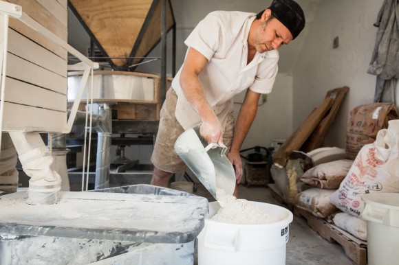 Baker Andrew Heyn of Elmore Mountain Bread scoops flour he's just milled. Credit: Monica Frisell