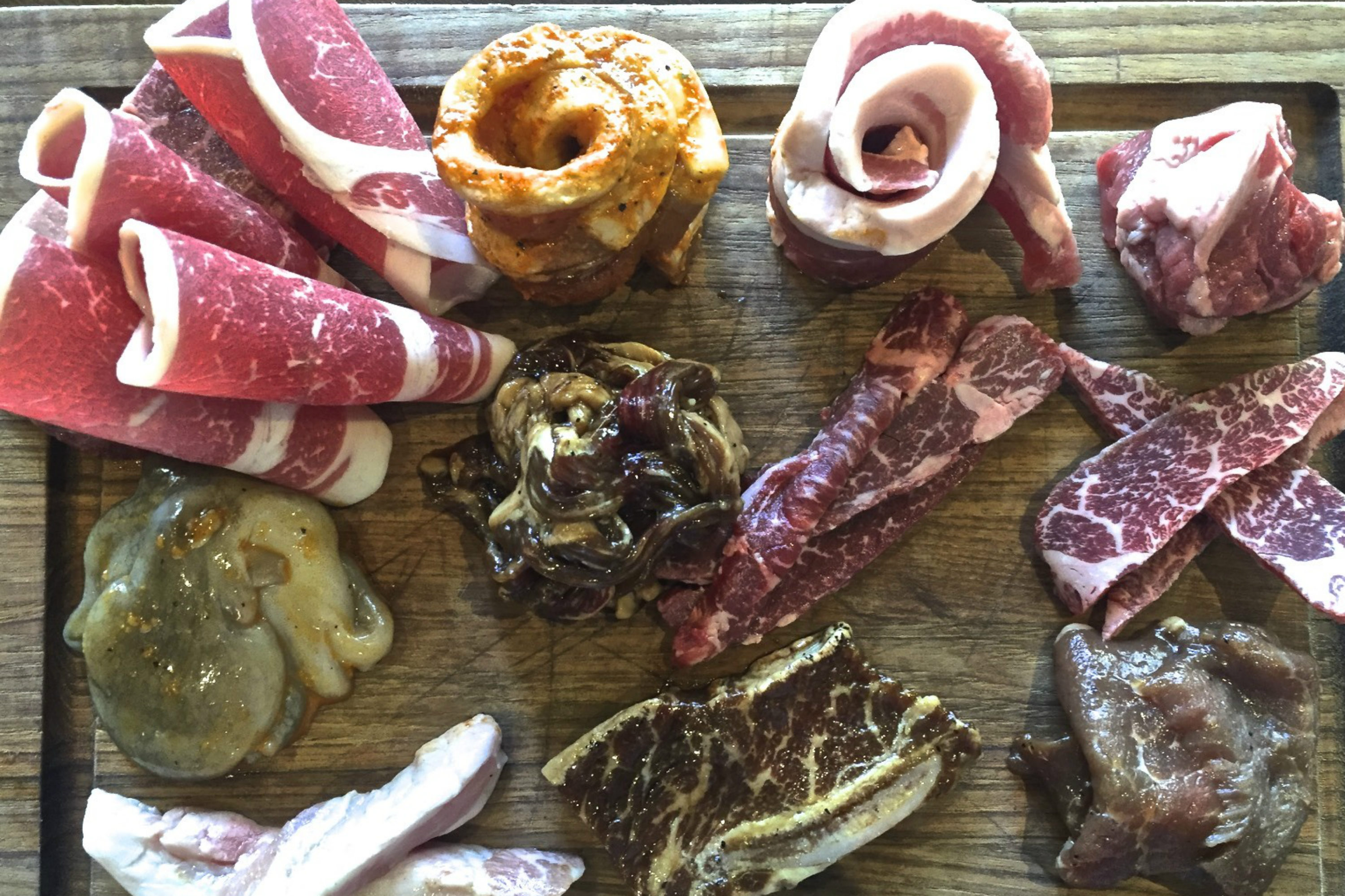 Korean barbecue offerings at Hanjip. Top row: ribeye, brisket, marinated pork belly, pork belly, lamb. Middle row: baby octopus, beef bulgogi, skirt steak, short rib. Bottom row: pork jowl, marinated short rib, marinated pork shoulder. Credit: Copyright 2016 David Latt