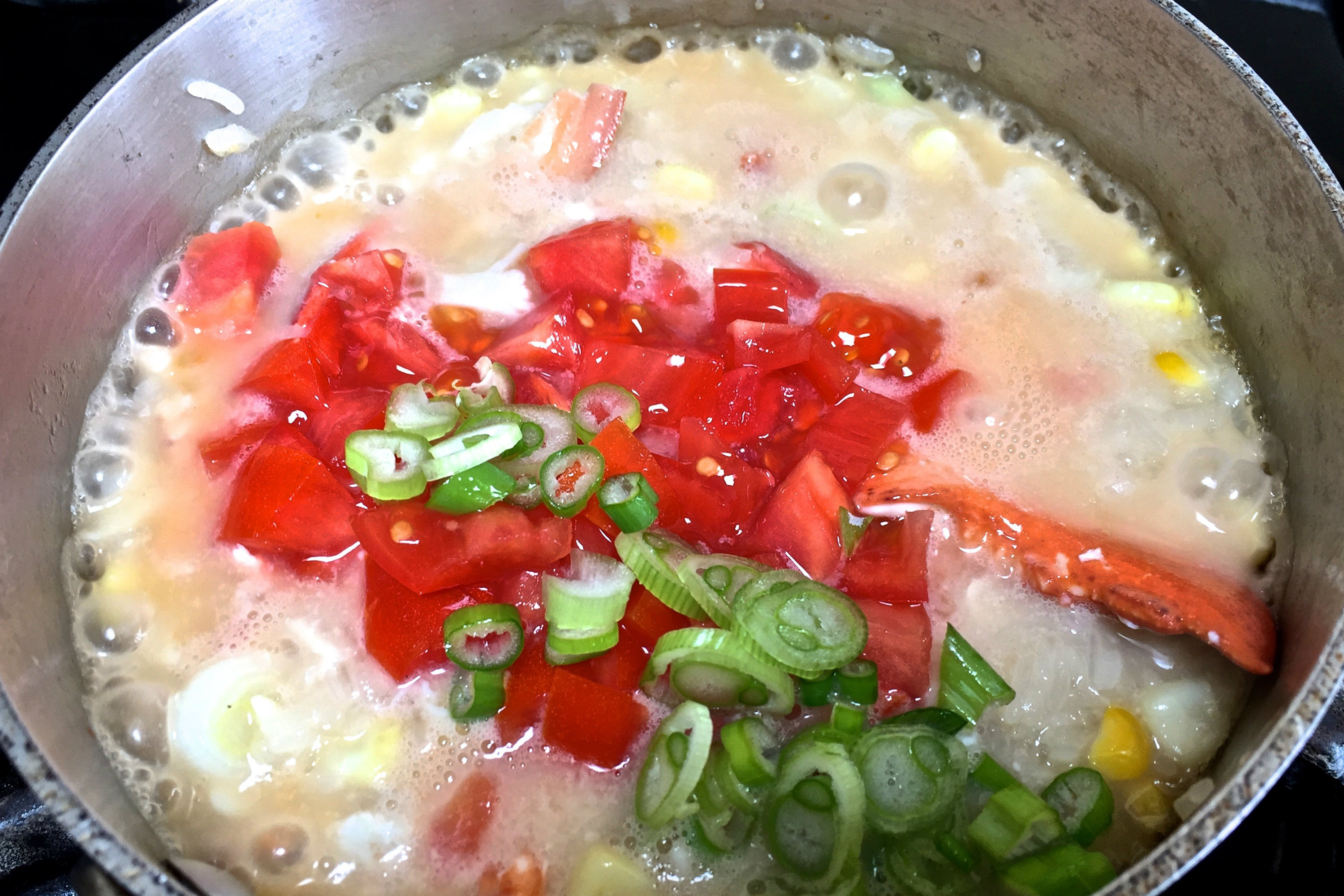 Corn-Lobster Congee in stock pot with corn kernels, lobster meat, chopped tomatoes and sliced scallions. Credit: Copyright 2016 David Latt